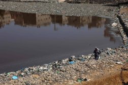 فلسطيني يسير بين القمامة على حافة بركة امتلأت بالمياه الآسنة في مدينة غزة (أ.ف.ب)